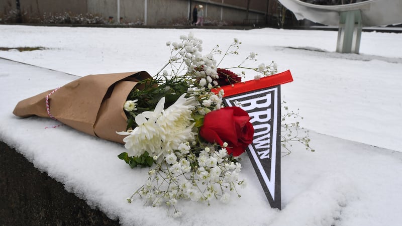 A bouquet of flowers rests on snow, Sunday, Dec. 14, 2025, on the campus of Brown University...