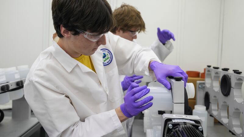 Jackson Quinn, foreground, places a bottle contains a PFAS water sample into a rotator,...