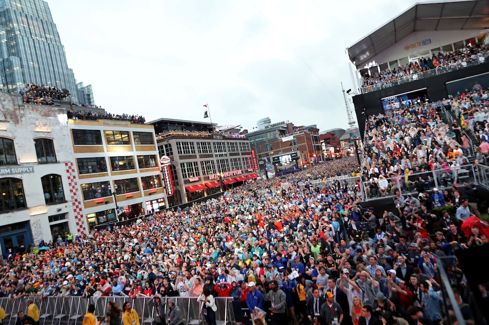 Fans line up Broadway in the rain to watch the first round of the NFL football draft, in...