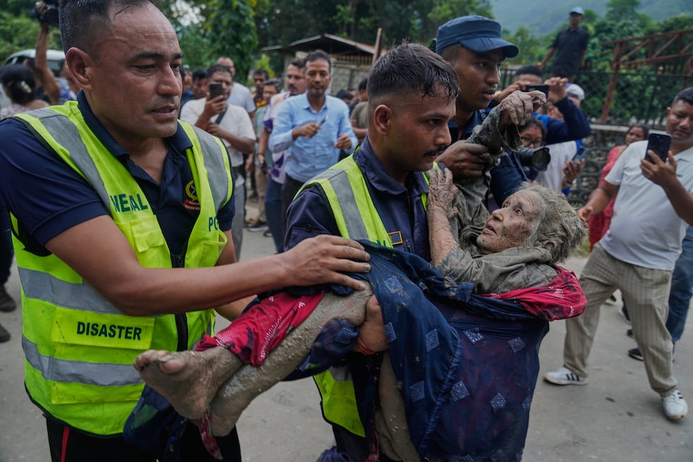 Rescuers carry a victim of flash flooding to safety along the Trishuli River in Nepal's...